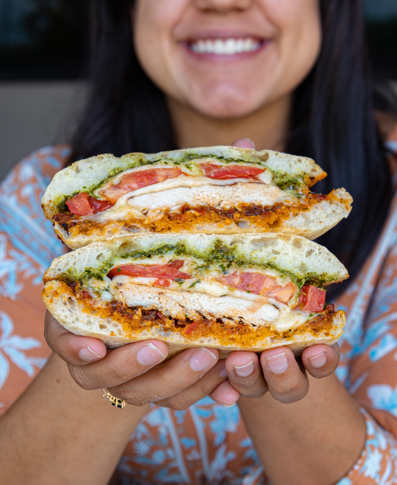 A guest holding a chicken pesto panini cut in half